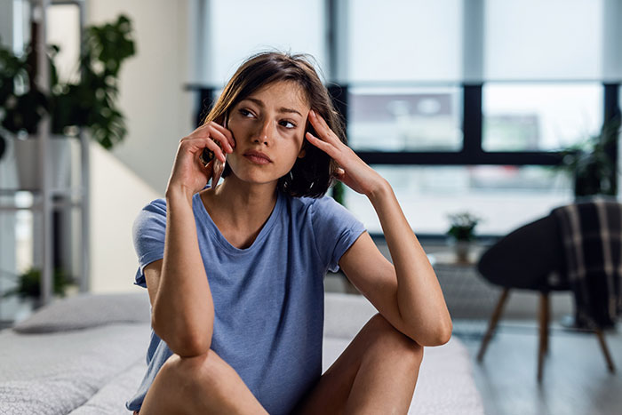 Young woman looking frustrated while talking on phone, reflecting on friends who were actually total jerks.