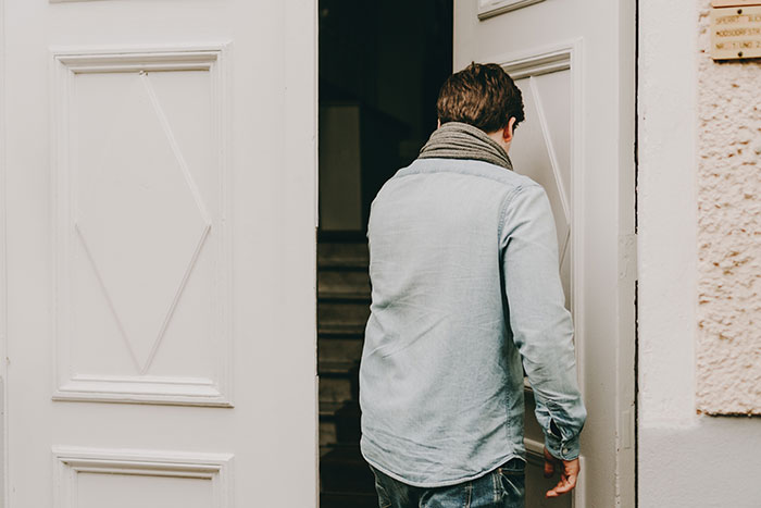 Man wearing a denim shirt and scarf opening a white door, highlighting cycle trip choice over watching his daughter. Man wearing a denim shirt and scarf opening a white door, highlighting cycle trip choice over watching his daughter.