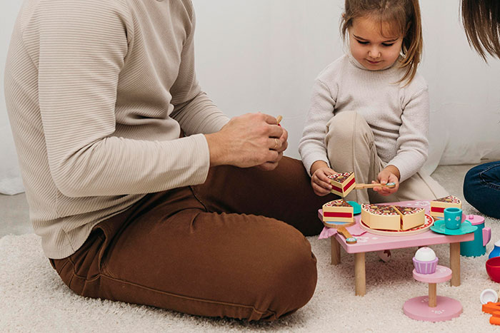 Man and daughter sitting on the floor playing with toy cake, highlighting father choosing cycle trip over watching daughter. Man and daughter sitting on the floor playing with toy cake, highlighting father choosing cycle trip over watching daughter.
