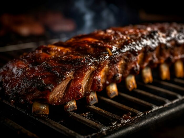 Close-up of ribs grilling with smoky glaze, unrelated to people who deal with dead bodies uncovering weird things.