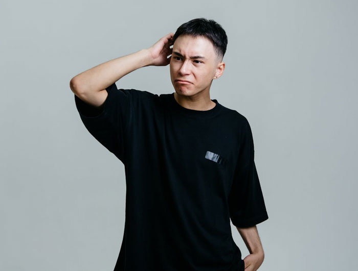 Young man wearing black shirt with frustrated expression, representing conflict over golden child stealing brother&rsquo;s gifts.