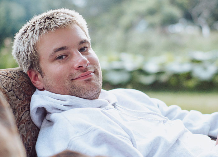 Young man in a white hoodie relaxing outdoors, representing men getting brutally honest about topics they never share with women. - 16