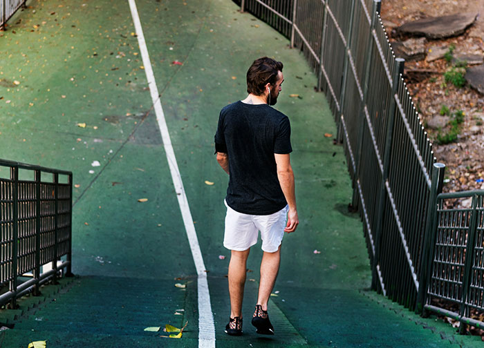 Man wearing black shirt and white shorts walking down a green path, reflecting on what men never tell women about being stupid and ugly - 43