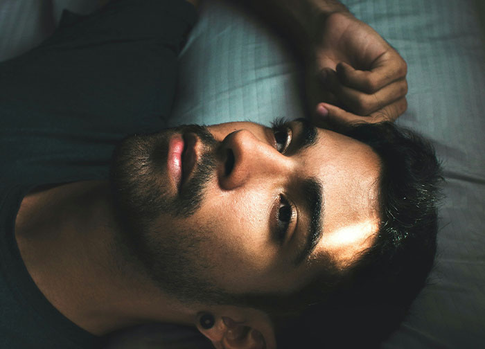 A man lying down with a thoughtful expression, illustrating men being brutally honest about what they never tell women. - 35