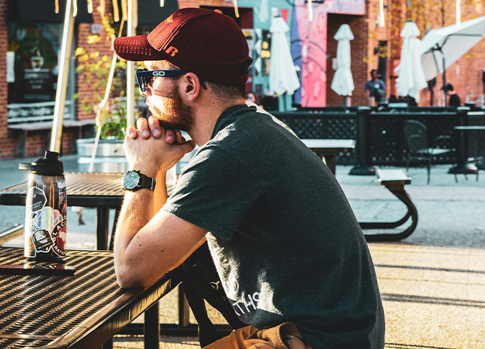 Man wearing sunglasses and cap sitting outdoors at a table, representing men getting brutally honest about what they never tell women. - 9