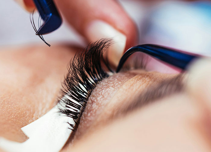 Close-up of a person having eyelash extensions applied, illustrating beauty and appearance topics. - 4