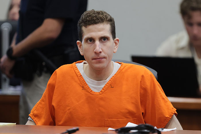 Man in an orange prison jumpsuit sitting at a courtroom table during the Idaho massacre victim trial of Bryan Kohberger. - 1
