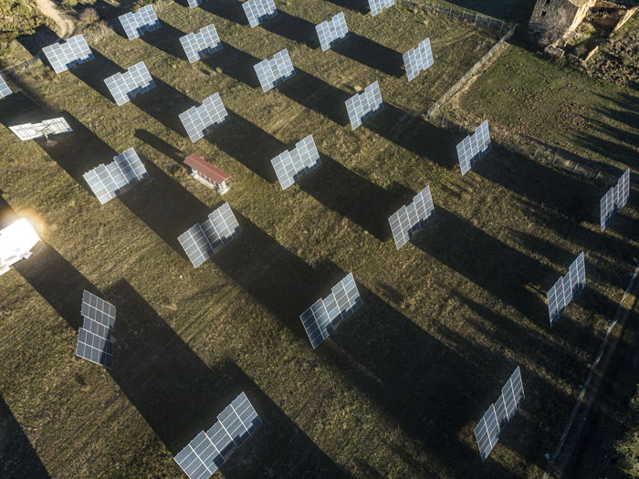 Aerial view of solar panels installed on grassland casting long shadows at sunset during solar farm construction. Aerial view of solar panels installed on grassland casting long shadows at sunset during solar farm construction.