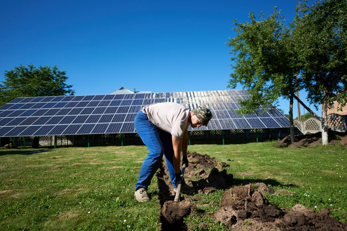 Worker digging near solar panels at a solar farm construction site uncovering a 5000-year-old ancient fortress site. Worker digging near solar panels at a solar farm construction site uncovering a 5000-year-old ancient fortress site.