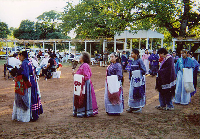 Native American women dressed in traditional clothing participating in a cultural event, highlighting language risks of extinction. - 2