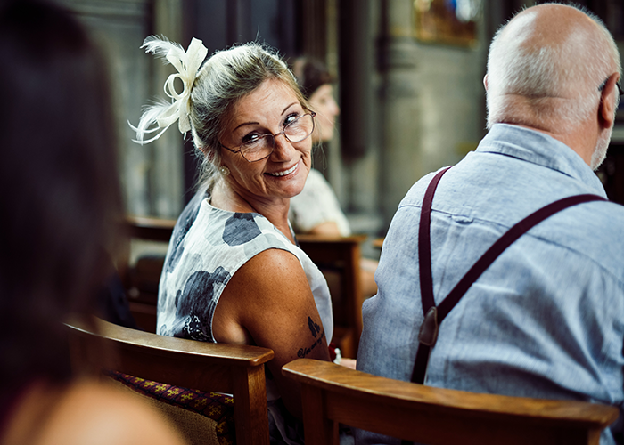 Woman smiling with a feathered hair accessory at a wedding, illustrating the call off wedding weird family tradition concept.