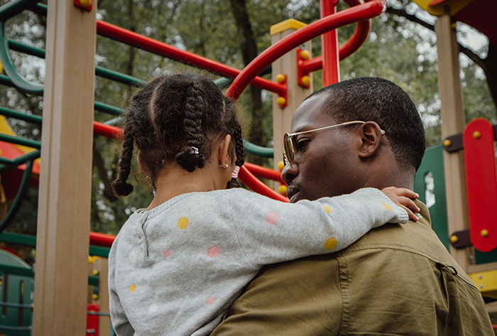 Man holding child at playground, highlighting child support and concerns about kids wearing tattered clothes and CPS involvement. - 17