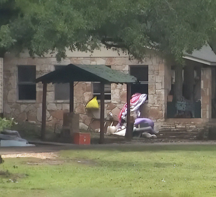 Stone building with scattered belongings outside, highlighting flood-stricken Camp Mystic controversy and official sparks outrage.