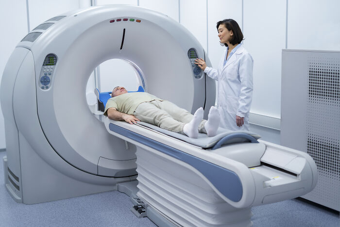 A doctor preparing a patient for a cancer symptoms scan using advanced medical imaging equipment in a hospital.