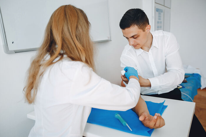 Doctor examining patient's arm in a clinical setting, discussing cancer symptoms during a medical consultation.