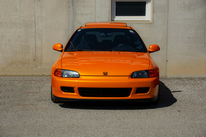 Orange sports car parked in front of a concrete wall, related to car thieves stopped by clever tricks. - 1