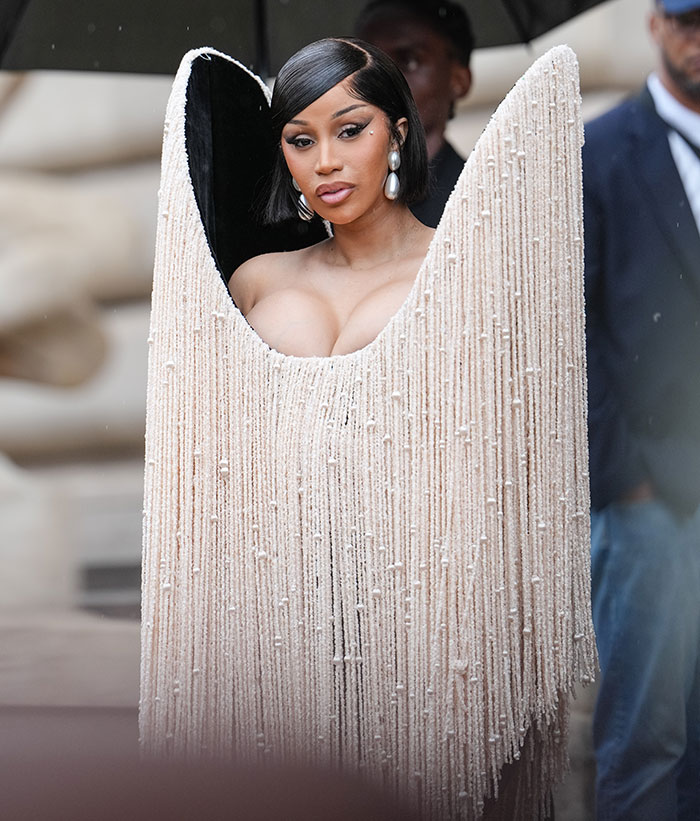 Celebrity wearing a bold fringe dress resembling a floor lamp at Paris Fashion Week 2025, showcasing viral fashion looks. Celebrity wearing a bold fringe dress resembling a floor lamp at Paris Fashion Week 2025, showcasing viral fashion looks.