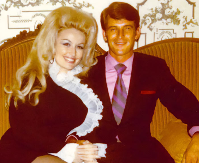 Vintage photo of a smiling couple sitting on a couch, representing stars we've lost this year by July.