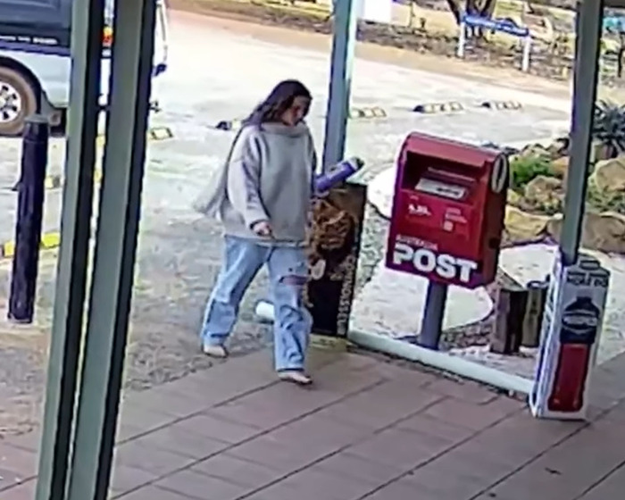 Backpacker in casual clothes walking near a post box in Australian outback area after unexplained behaviour incident.