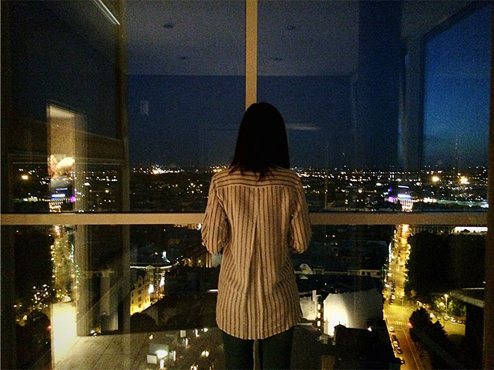 Woman looking out over city lights at night, symbolizing reflections from casino workers sharing stories.
