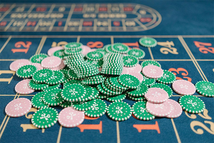 Green and pink casino chips scattered on a roulette table representing stories from casino workers in a gaming environment