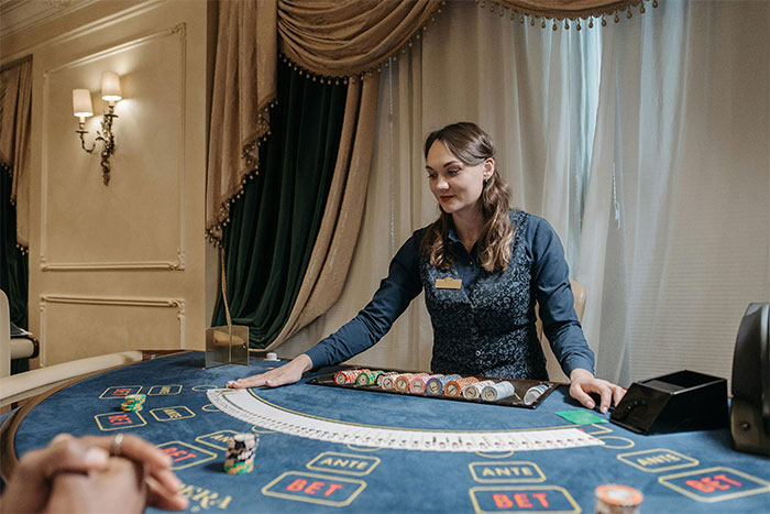 Casino worker dealing cards at gaming table, showcasing chips and cards in an elegant casino setting.