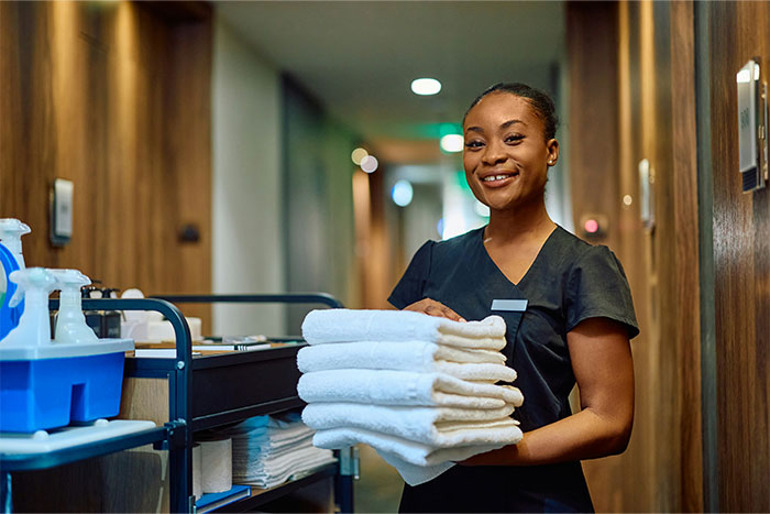 Casino worker smiling and holding fresh towels in a hallway, representing stories shared by 90 casino employees.