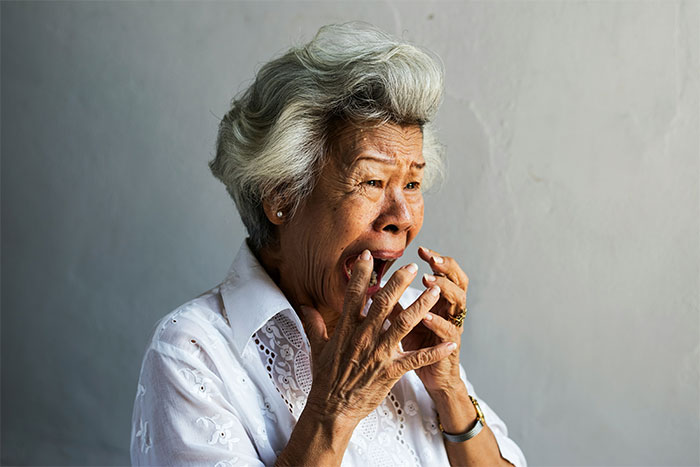 Elderly woman in white shirt showing shock and emotion, reflecting casino workers' craziest and heartbreaking stories.
