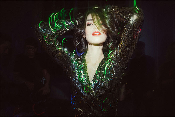 Woman in sequined dress dancing under green casino lights, capturing vibrant casino workers' experiences and stories.