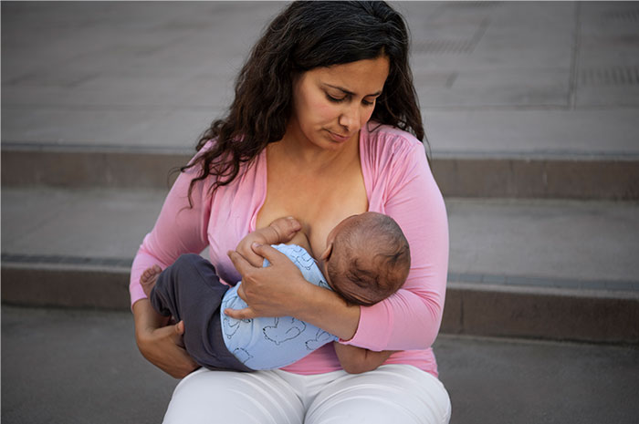 Woman breastfeeding her baby while sitting on concrete steps, illustrating heartfelt moments shared by casino workers.