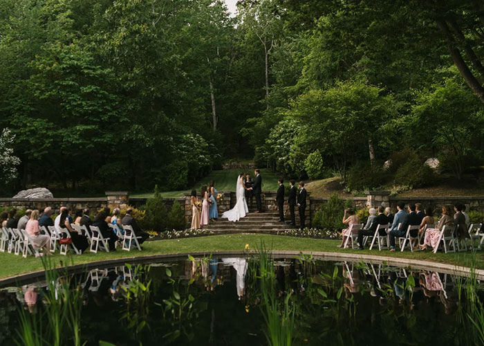 Outdoor wedding ceremony with bride and groom exchanging vows, surrounded by guests and lush greenery before reception chaos.