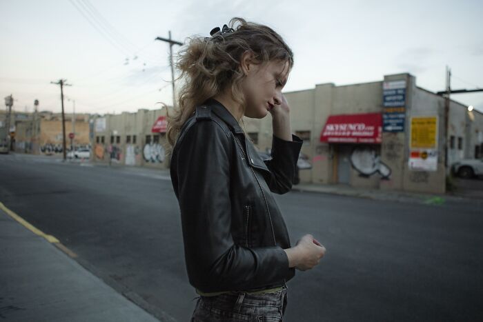 Young woman in a leather jacket standing on an empty street, reflecting on truckers' craziest things seen stories. - 26