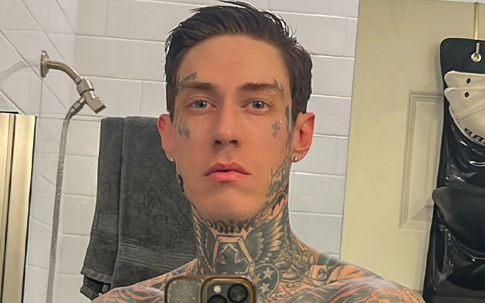Tattooed man taking a bathroom selfie illustrating wild things celebrities have done after a breakup and men avoiding therapy. - 13