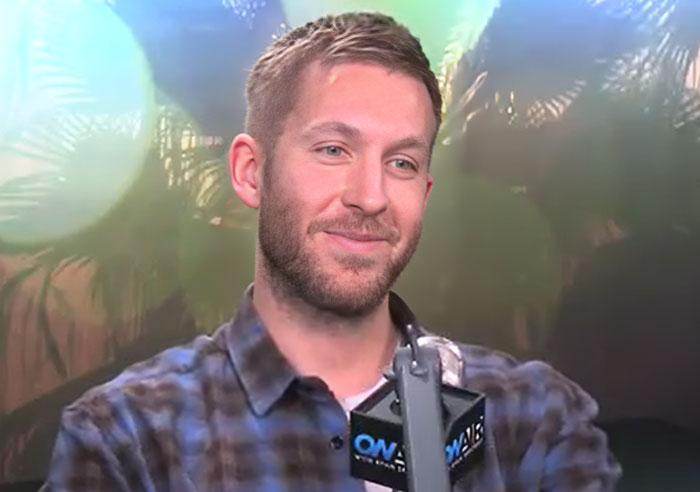 Man with beard and plaid shirt speaking into a microphone about men doing anything but going to therapy after breakups. - 22