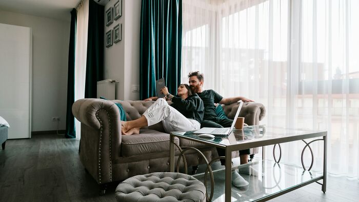 Couple relaxing on sofa in living room, highlighting refusal to be go-to nanny on friends’ couples trip. - 1