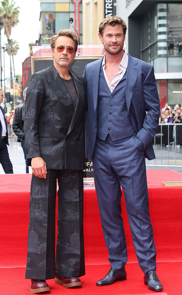 Two tall stars standing on a red carpet event, showcasing their super tall height and fashionable suits.
