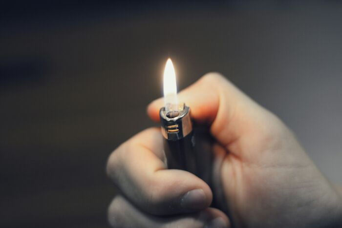 Close-up of a hand holding a lighter with flame, symbolizing eerie discoveries by people who deal with dead bodies.