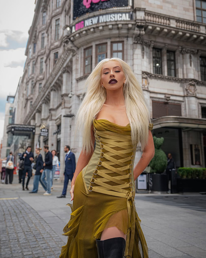 Christina Aguilera posing in a racy olive green dress during a photoshoot fueling Ozempic rumors outdoors. - 9