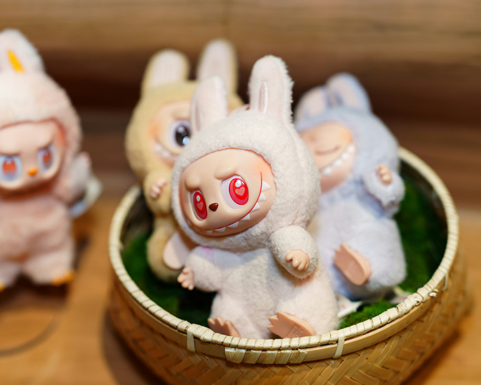 Labubu figures wearing bunny costumes with red eyes displayed in a basket amid dark conspiracy concerns.