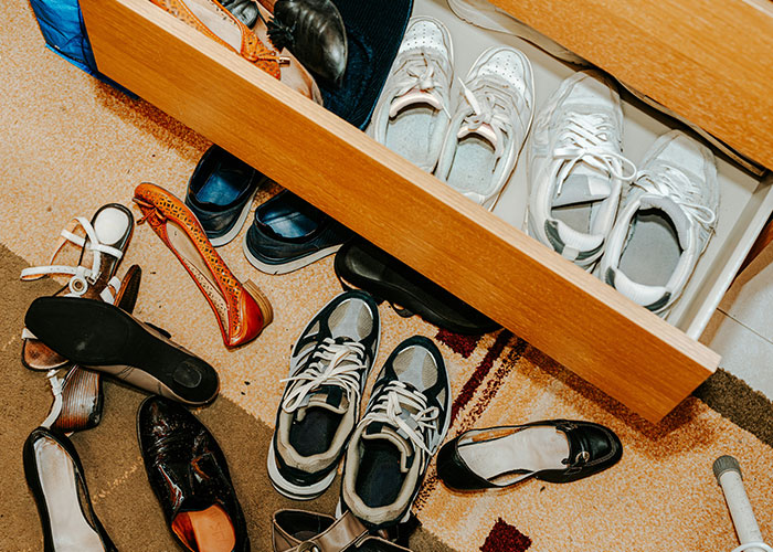 Messy college students' shoes scattered on the floor and inside a drawer, illustrating roommates finally picking up after themselves. - 6