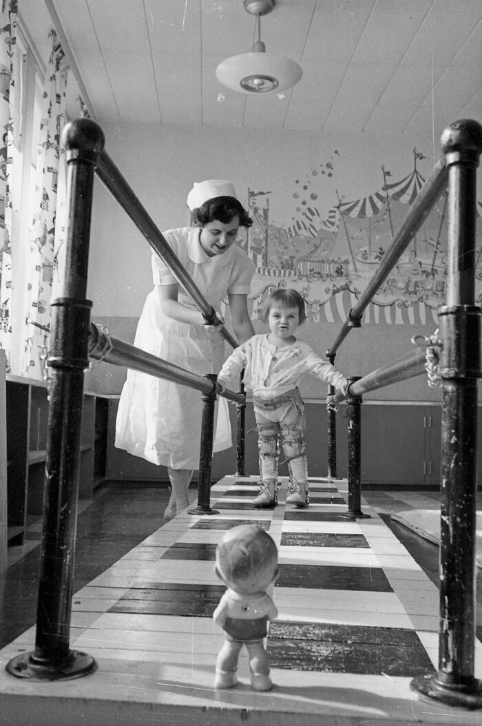 Vintage photo of a nurse helping a child walk with leg braces in a therapy room among unique old photos.