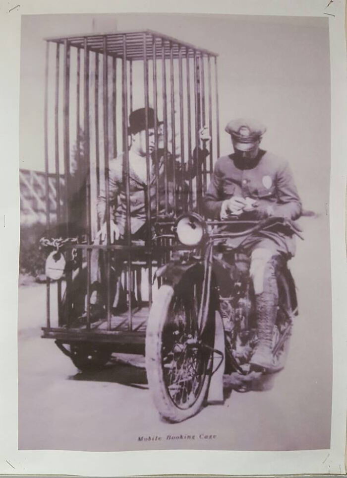 Vintage photo of a police officer on a motorcycle next to a man in a unique old photo jail cage sidecar.
