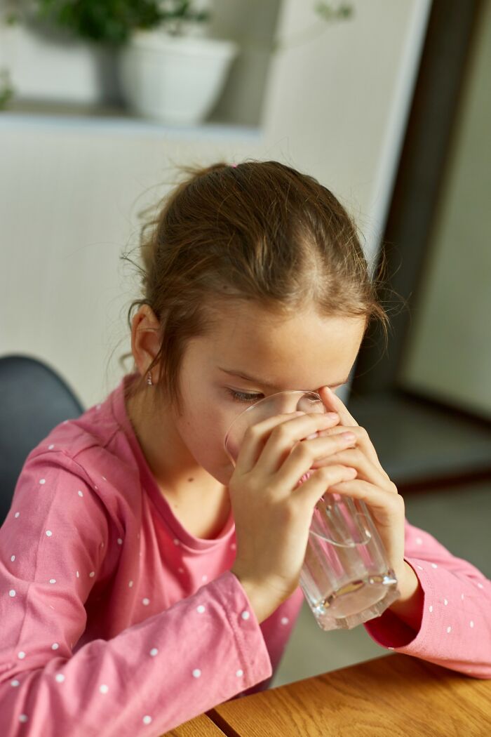 Young girl in a pink shirt drinking water, illustrating consequences of parents taking punishing kids way too far.