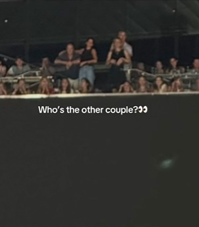 Blurry photo of a crowd at an event with a viral Coldplay couple standing closely together by a railing. Blurry photo of a crowd at an event with a viral Coldplay couple standing closely together by a railing.