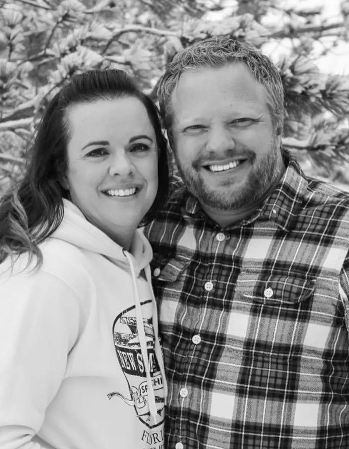 Black and white photo of a smiling couple outside with trees in the background, related to Colorado dentist red flags case. - 3