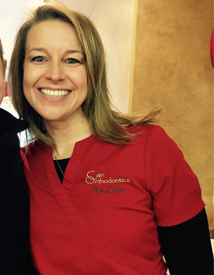 Woman in red dental scrubs smiling, representing Colorado dentist involved in red flags before wife’s murder case. - 7