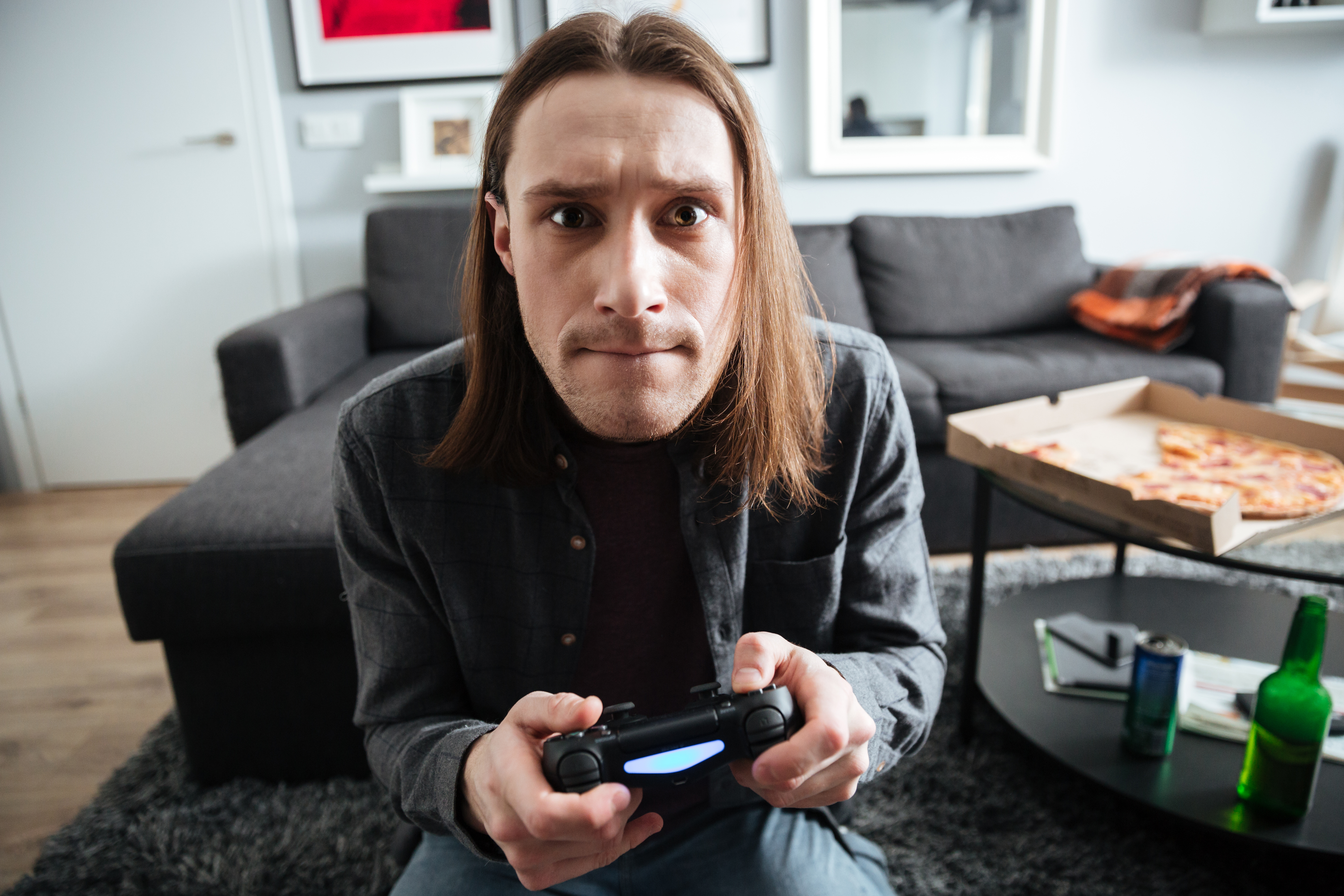Man intensely playing video games at home, illustrating guy picks video games over doctors visits with pregnant wife conflict. Man intensely playing video games at home, illustrating guy picks video games over doctors visits with pregnant wife conflict.