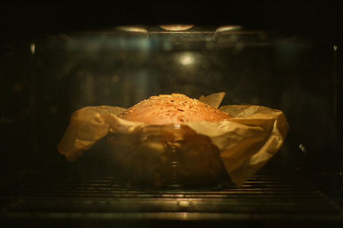Bread baking inside an oven with parchment paper, related to cooking myths and washing chicken discussion online.