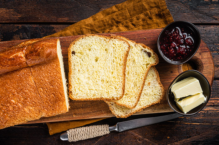Sliced bread on a wooden board with butter and berry jam, illustrating common cooking myths including washing chicken.