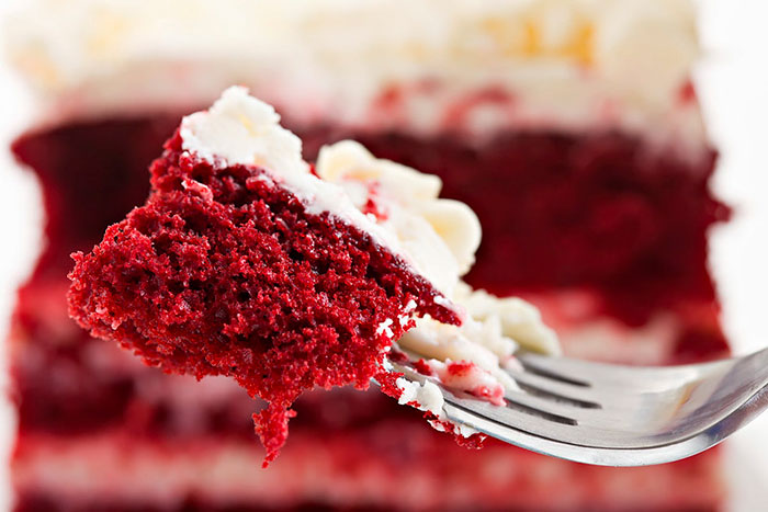 Close-up of a fork holding a piece of red velvet cake with cream frosting, unrelated to washing chicken cooking myths.